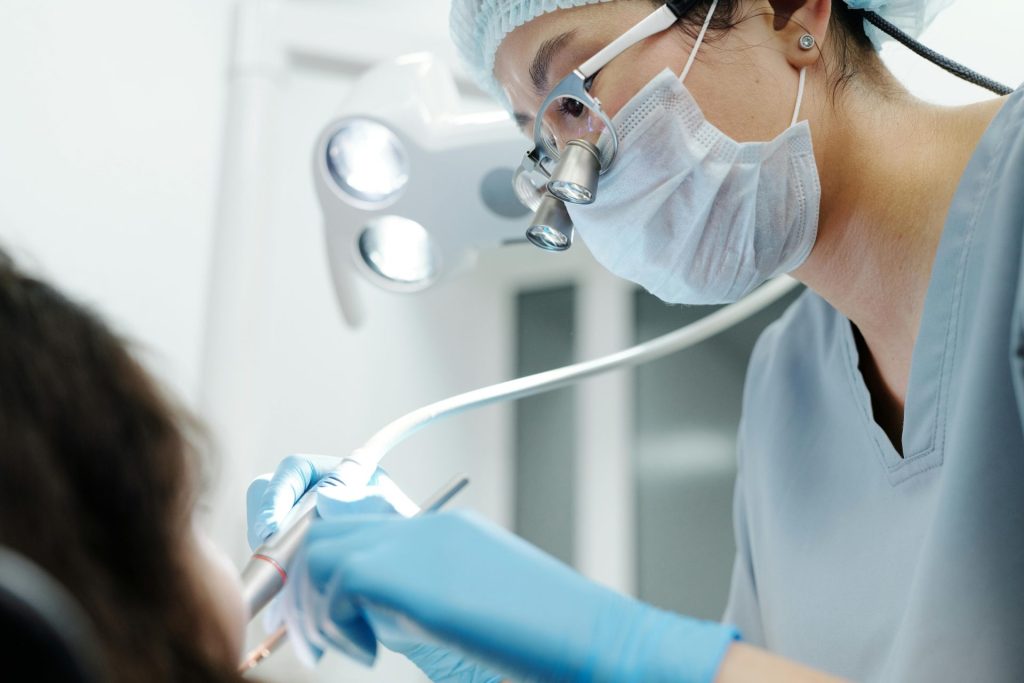 Close-up of a dentist wearing magnifying glasses, performing a dental procedure in a modern clinic.