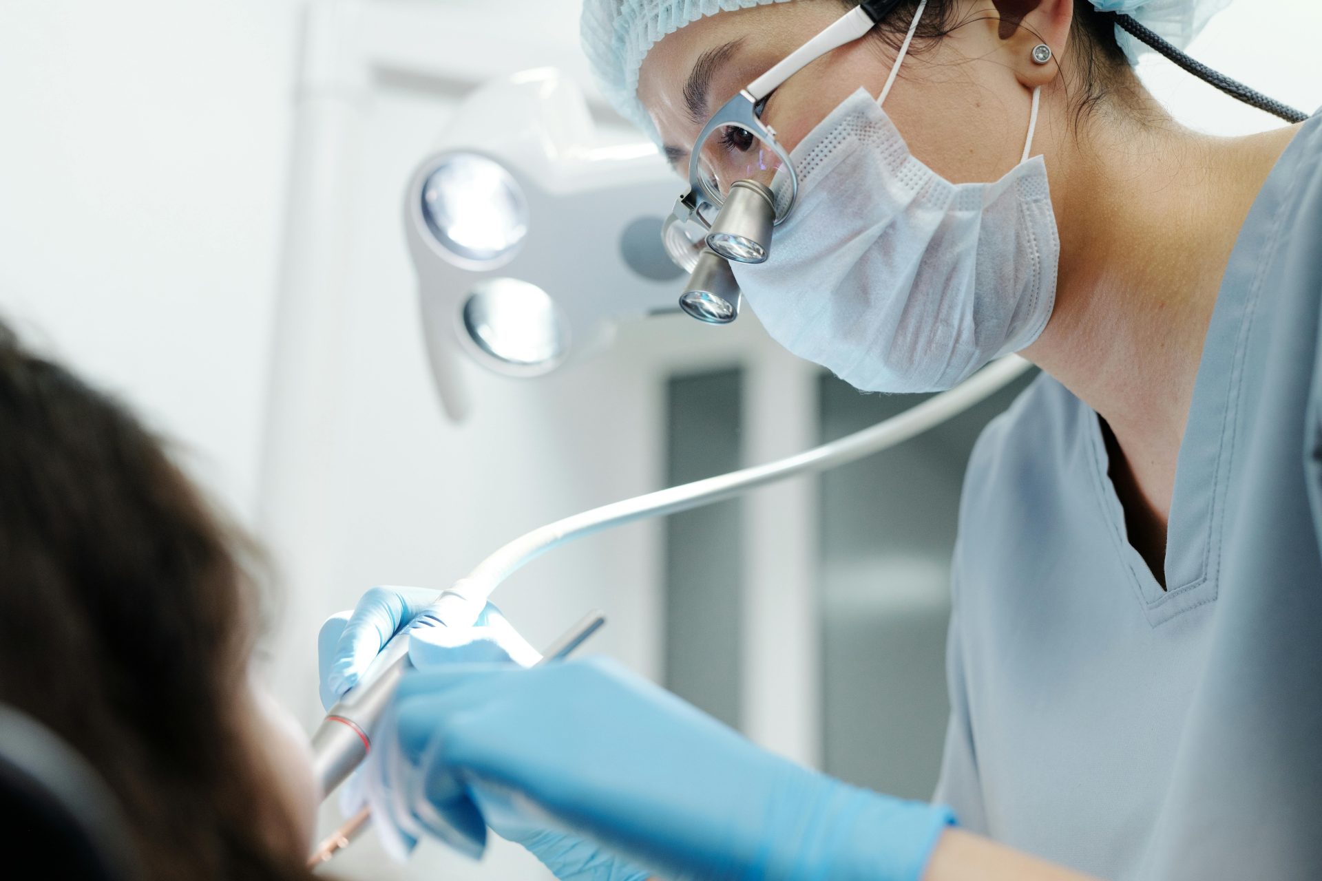 Close-up of a dentist wearing magnifying glasses, performing a dental procedure in a modern clinic.